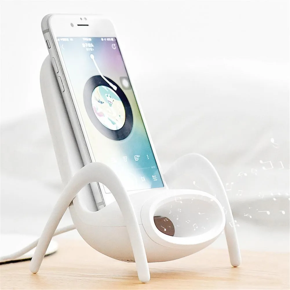 White chair-shaped wireless charging phone stand charging a smartphone on a desk