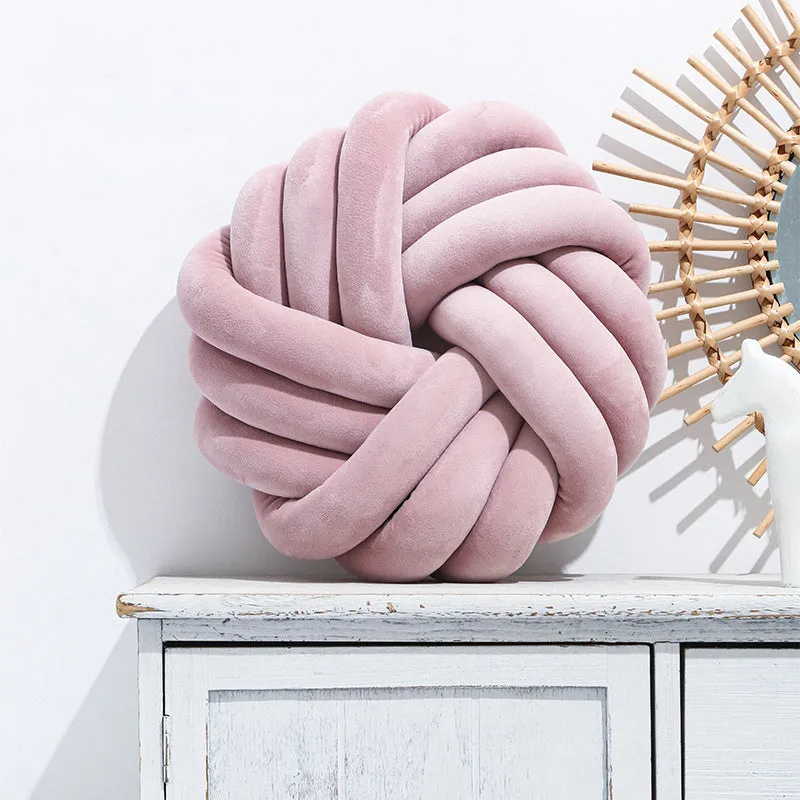 Square decorative cushion with knotted ball design in velvet fabric, shown in caramel colour