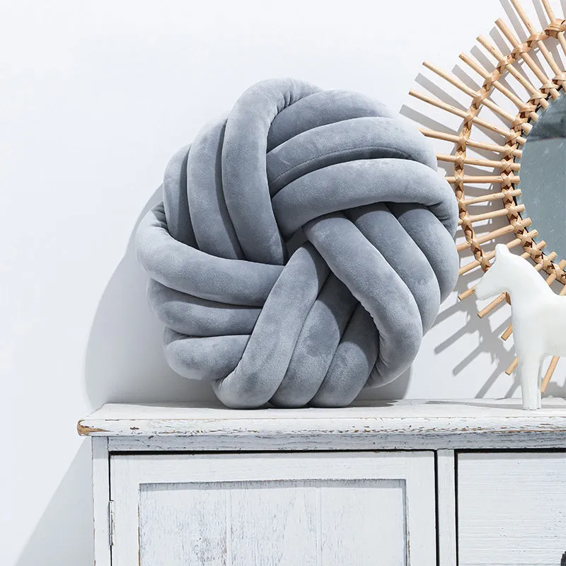 Square decorative cushion with knotted ball design in velvet fabric, shown in caramel colour
