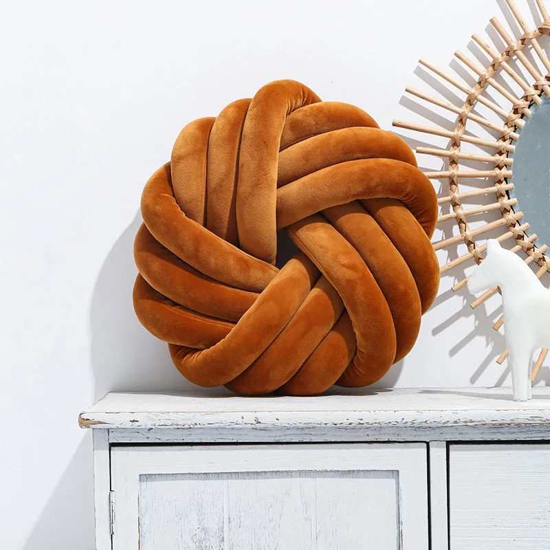 Square decorative cushion with knotted ball design in velvet fabric, shown in caramel colour