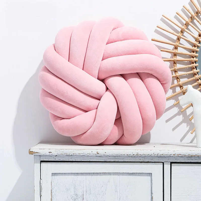 Square decorative cushion with knotted ball design in velvet fabric, shown in caramel colour