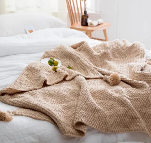 Simple modern fringed knit acrylic blanket in beige colour laid on a sofa, showing 130x170cm size.