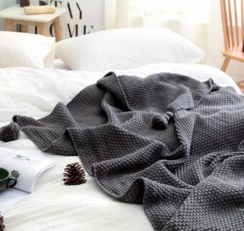 Simple modern fringed knit acrylic blanket in beige colour laid on a sofa, showing 130x170cm size.