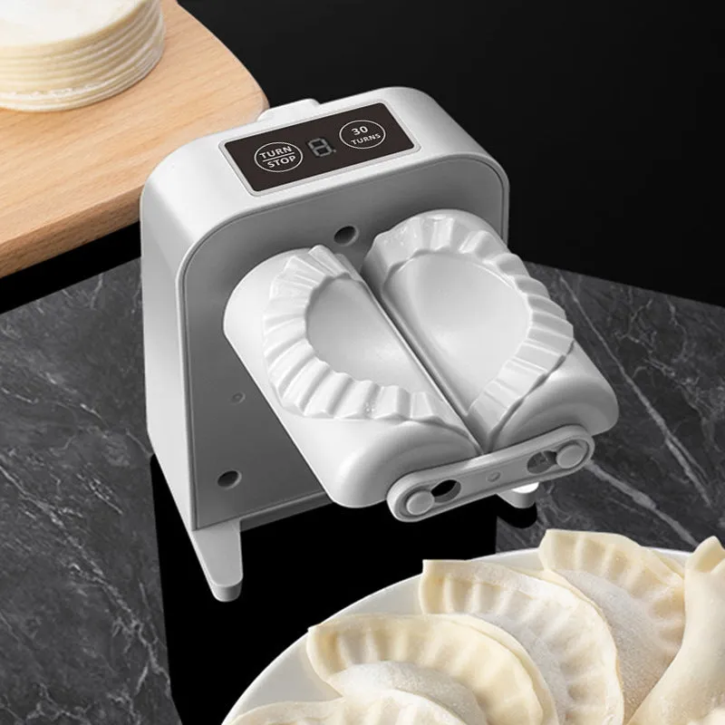 White automatic electric dumpling maker machine with USB cable on a kitchen counter.
