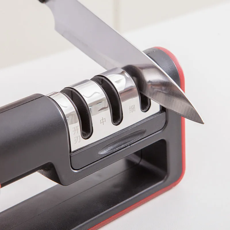 Black and red three-stage manual knife sharpener with rubber feet on base