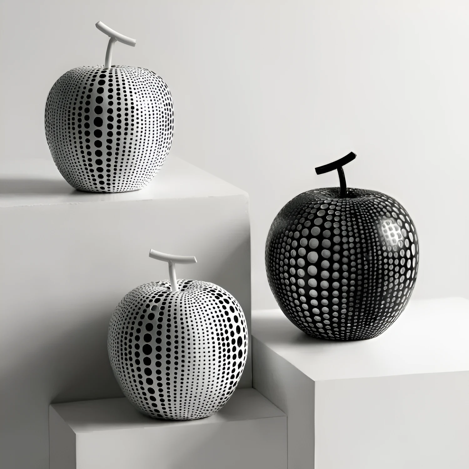 White and black resin apple and pear decorations showing high and low profile models on a wooden surface
