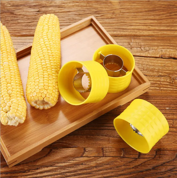 Yellow manual corn grinder thresher with corn-shaped PP handle on a kitchen worktop.