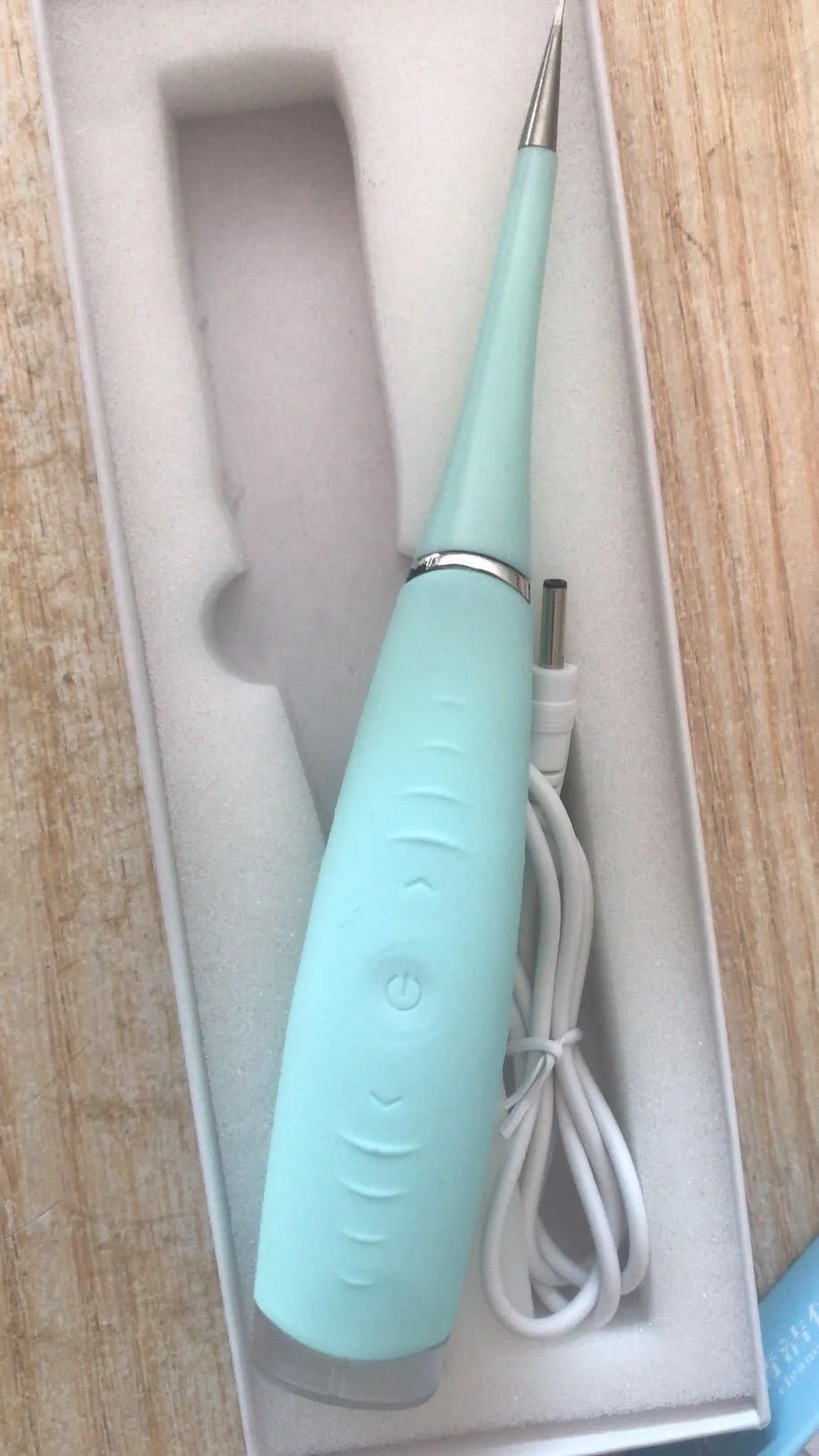 Pink or blue waterproof electric toothbrush care tool for removing dental calculus on a bathroom counter.