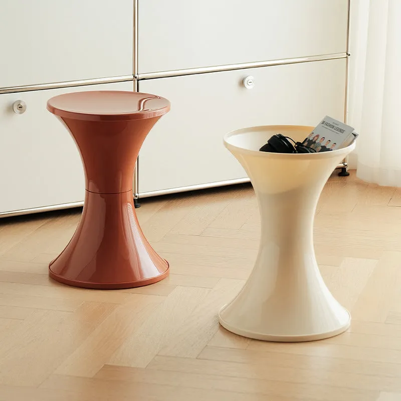 A white hourglass-shaped plastic shoe changing stool on a wooden floor.