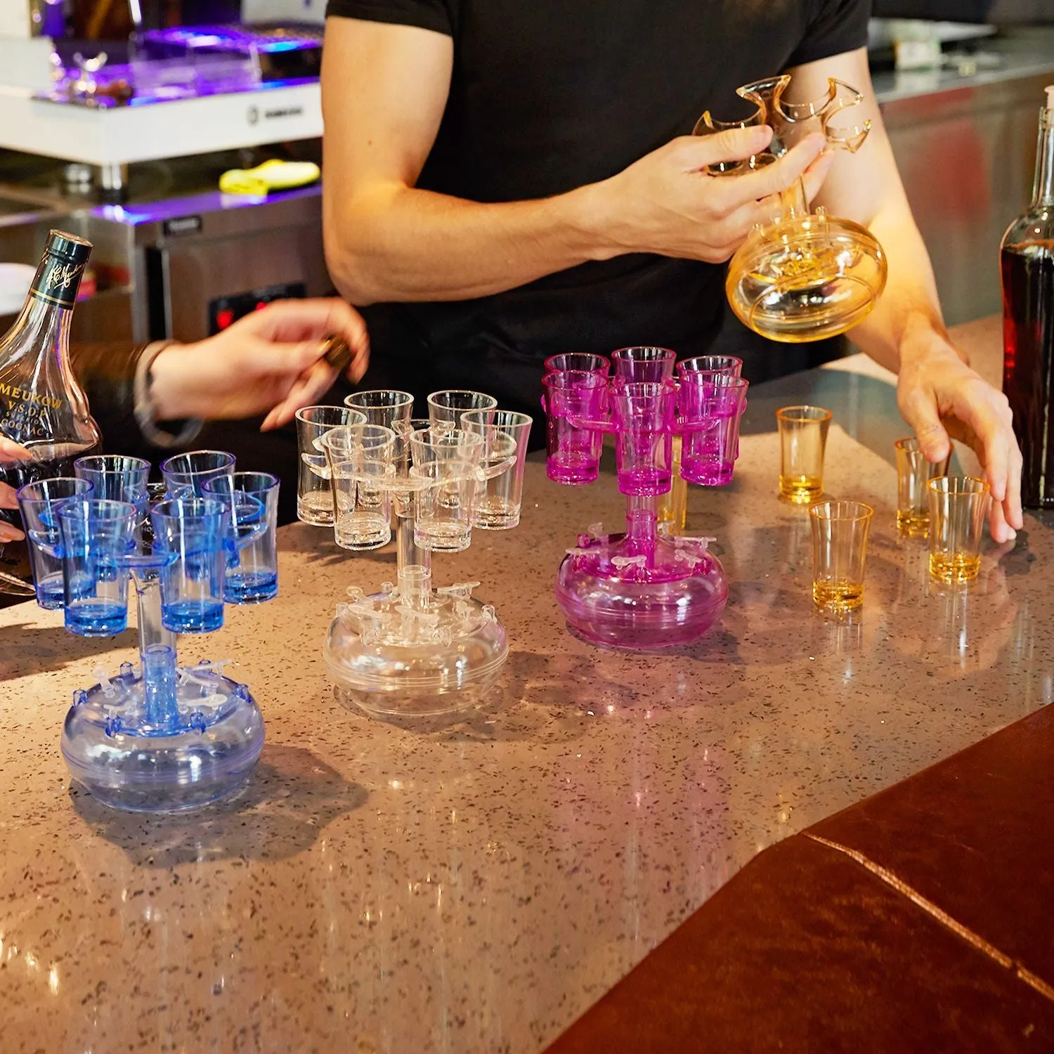 Six-shot glass dispenser rack made of clear PMMA acrylic holding six full shot glasses, shown in gold colour option.