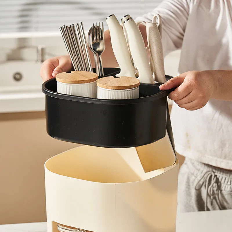 White rotating kitchen storage bucket with four-compartment spice box lid next to cutlery.