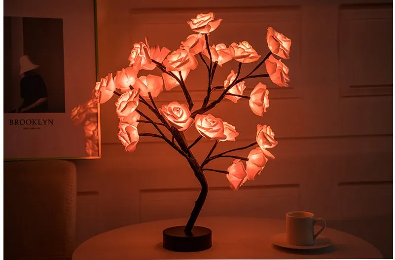 White and red rose flower shaped USB battery LED table lamp with warm white light on a table.
