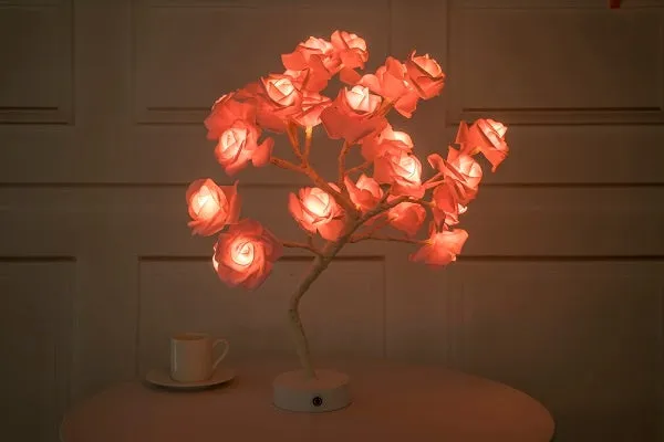 White and red rose flower shaped USB battery LED table lamp with warm white light on a table.