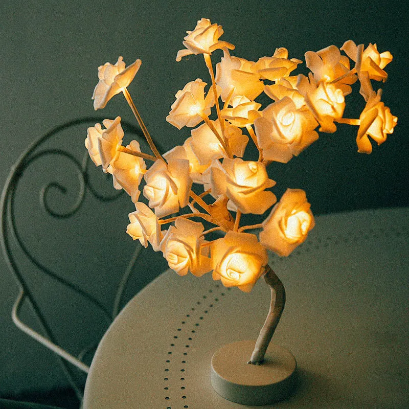 White and red rose flower shaped USB battery LED table lamp with warm white light on a table.