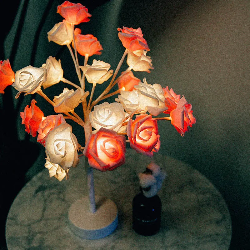 White and red rose flower shaped USB battery LED table lamp with warm white light on a table.