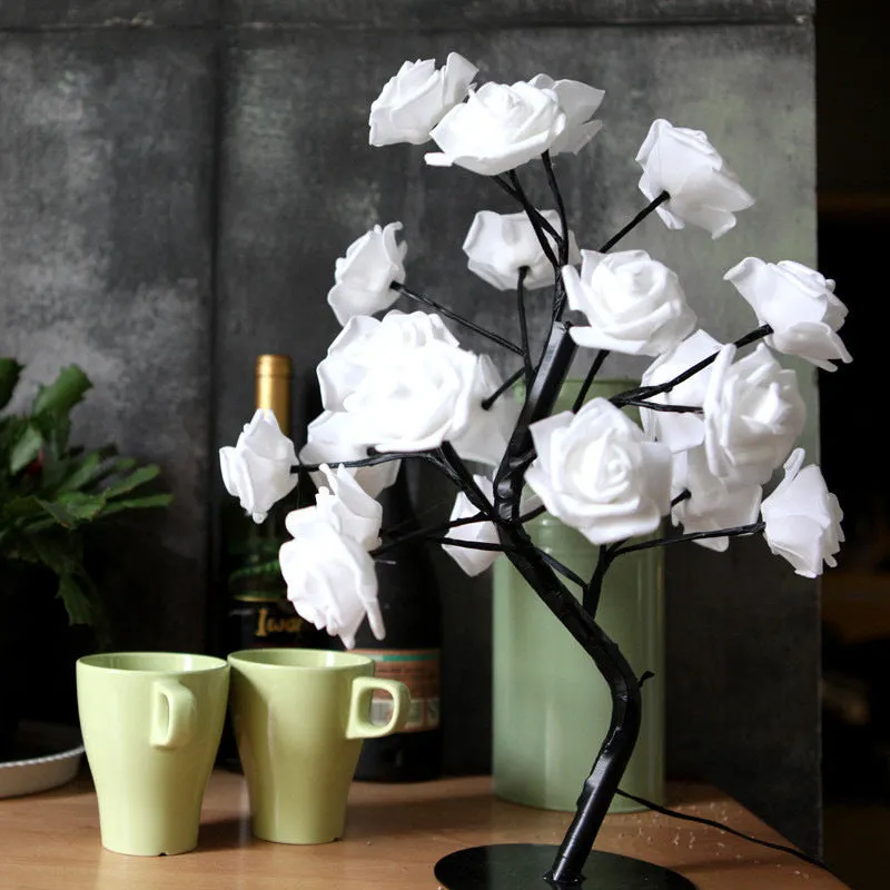 White and red rose flower shaped USB battery LED table lamp with warm white light on a table.