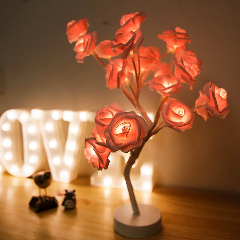 White and red rose flower shaped USB battery LED table lamp with warm white light on a table.