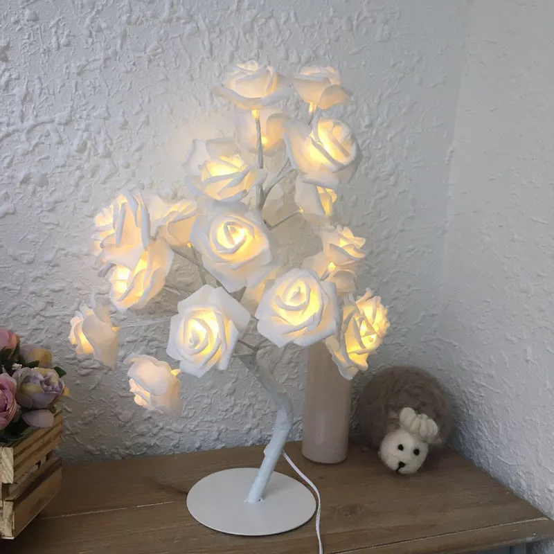 White and red rose flower shaped USB battery LED table lamp with warm white light on a table.