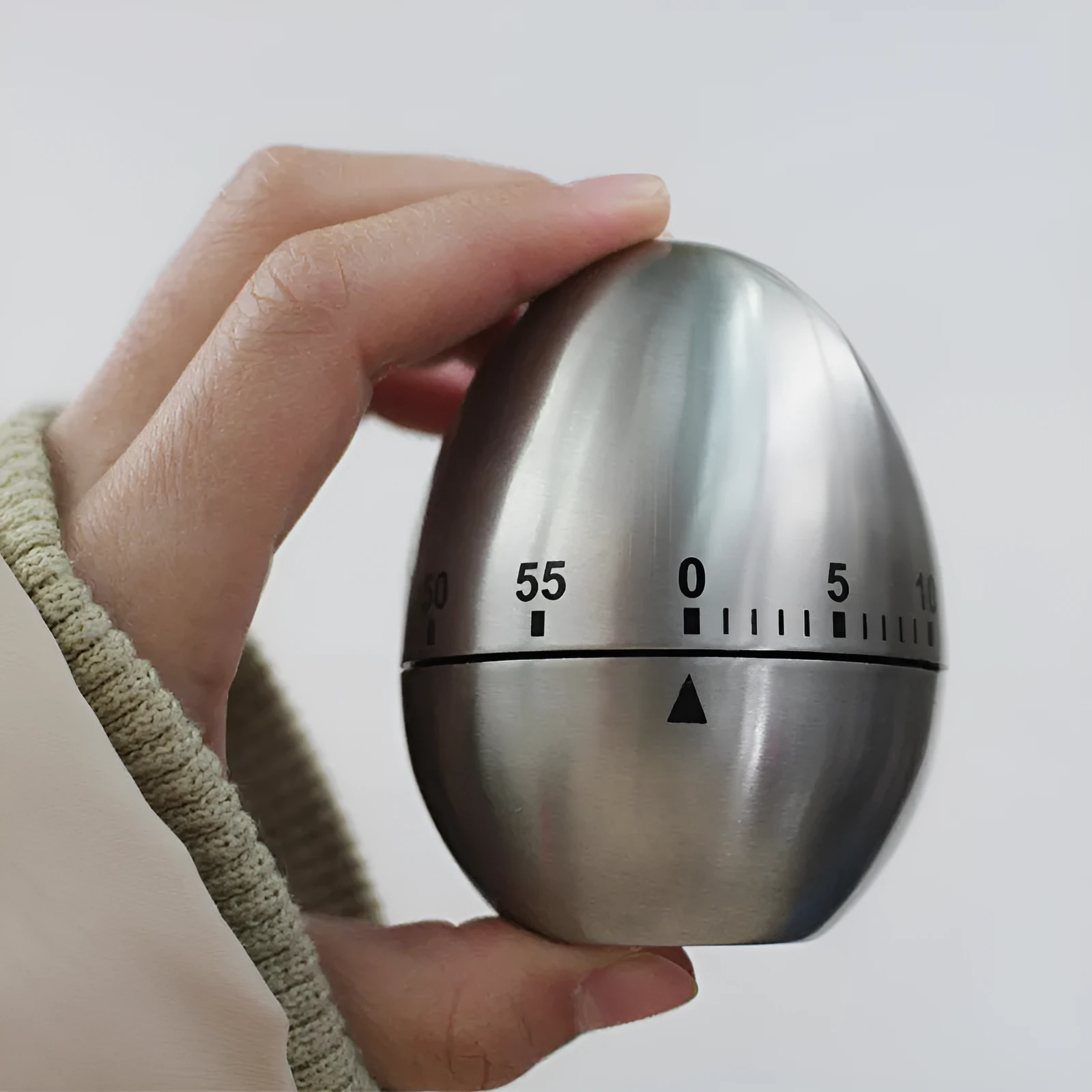 Stainless steel egg-shaped mechanical kitchen timer on a kitchen counter