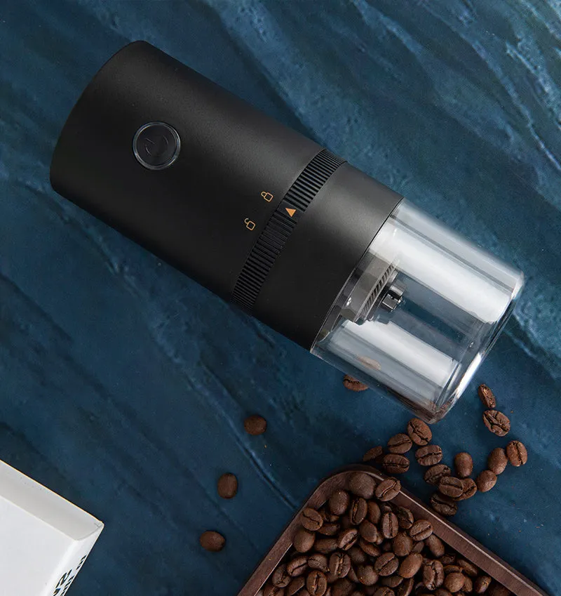 Black and white portable USB-C electric coffee grinder with transparent chamber on a kitchen counter