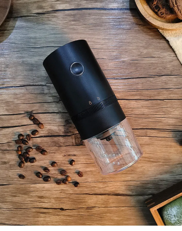 Black and white portable USB-C electric coffee grinder with transparent chamber on a kitchen counter