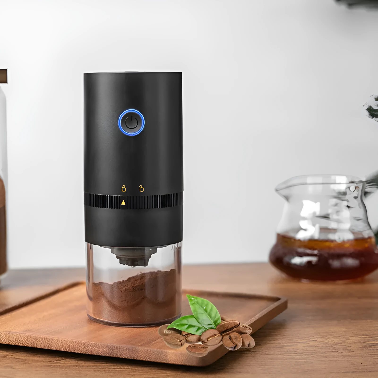 Black and white portable USB-C electric coffee grinder with transparent chamber on a kitchen counter
