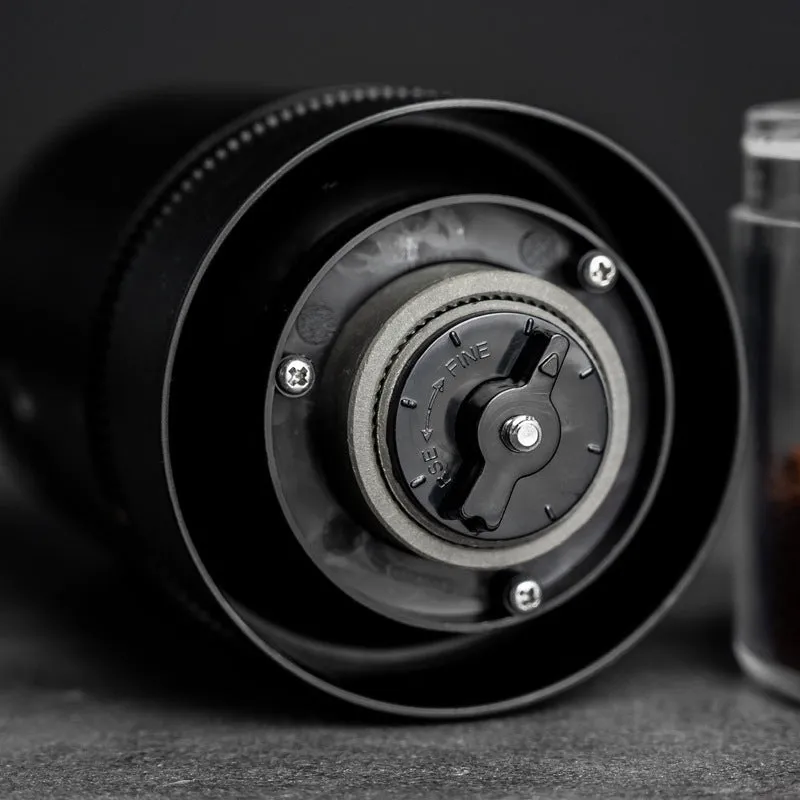 Black and white portable USB-C electric coffee grinder with transparent chamber on a kitchen counter