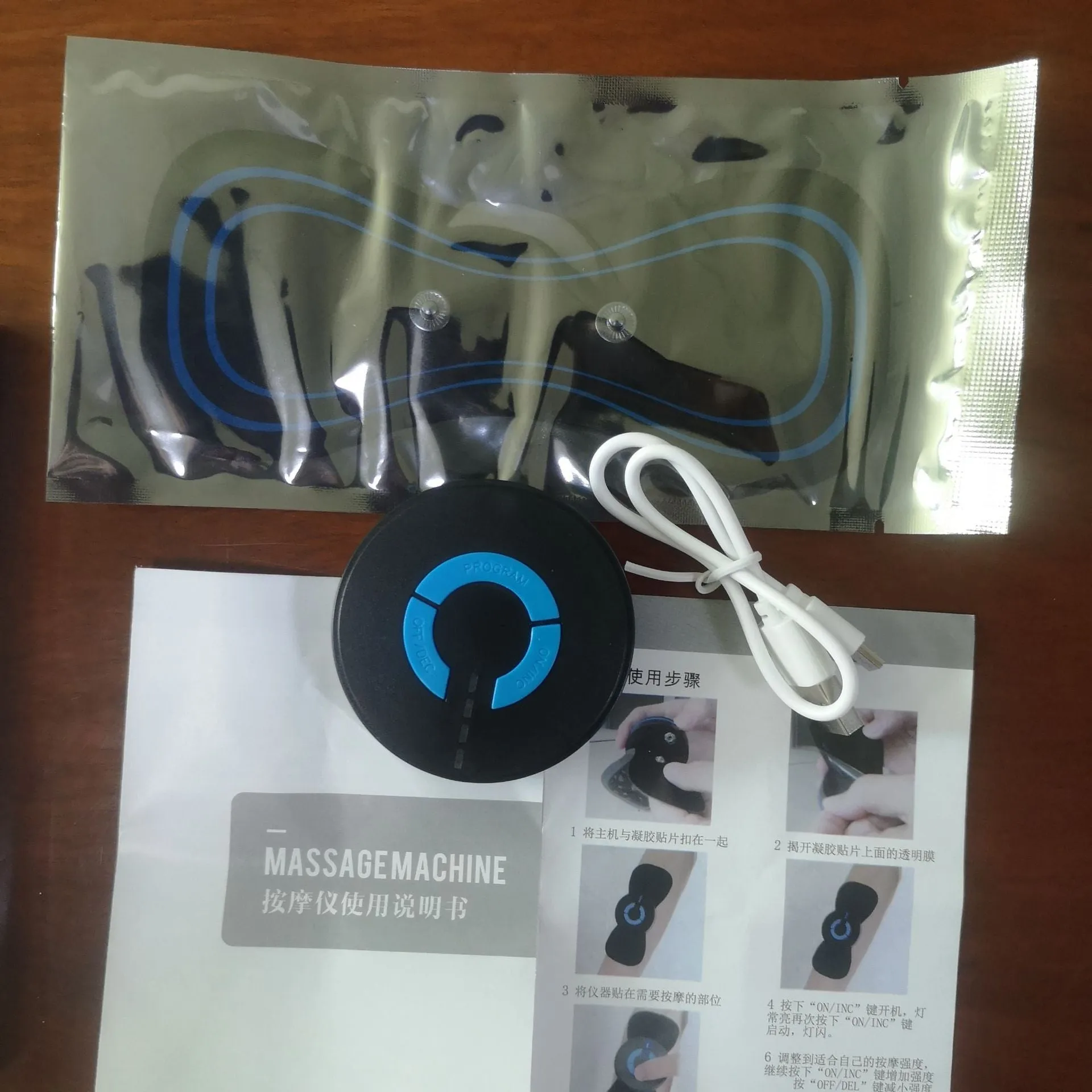 Black HQ-185 mini electric shoulder and neck massager with massage patch, shown next to a ruler for scale.
