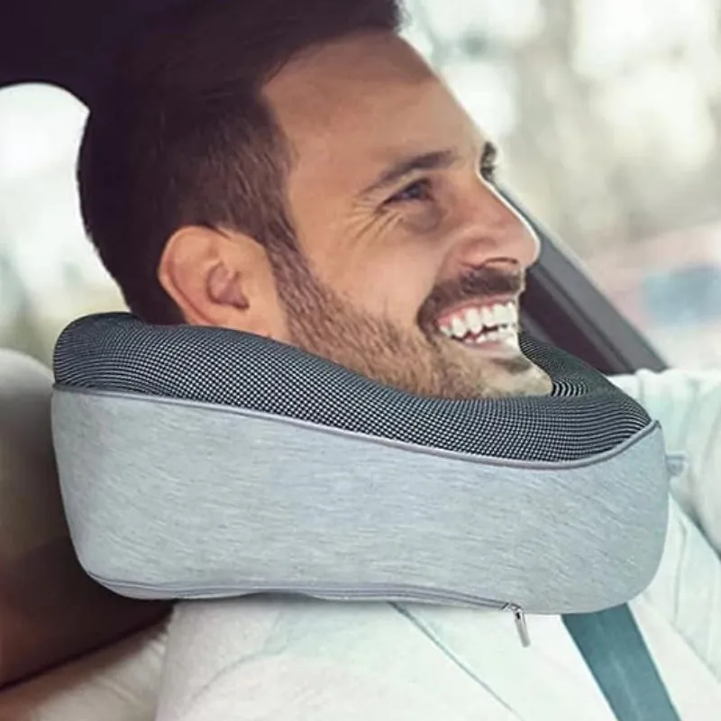 Navy blue U-shaped memory foam travel neck pillow rolled up next to its carry bag.