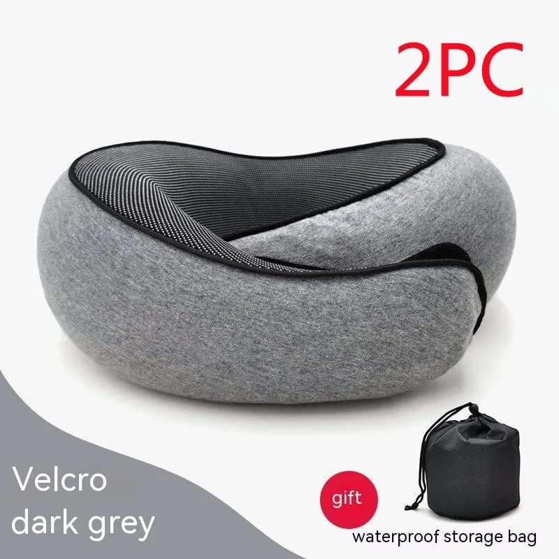 Navy blue U-shaped memory foam travel neck pillow rolled up next to its carry bag.