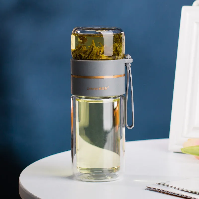Green double-wall glass water bottle with a stainless steel tea infuser insert and a black leak-proof lid with rope handle.