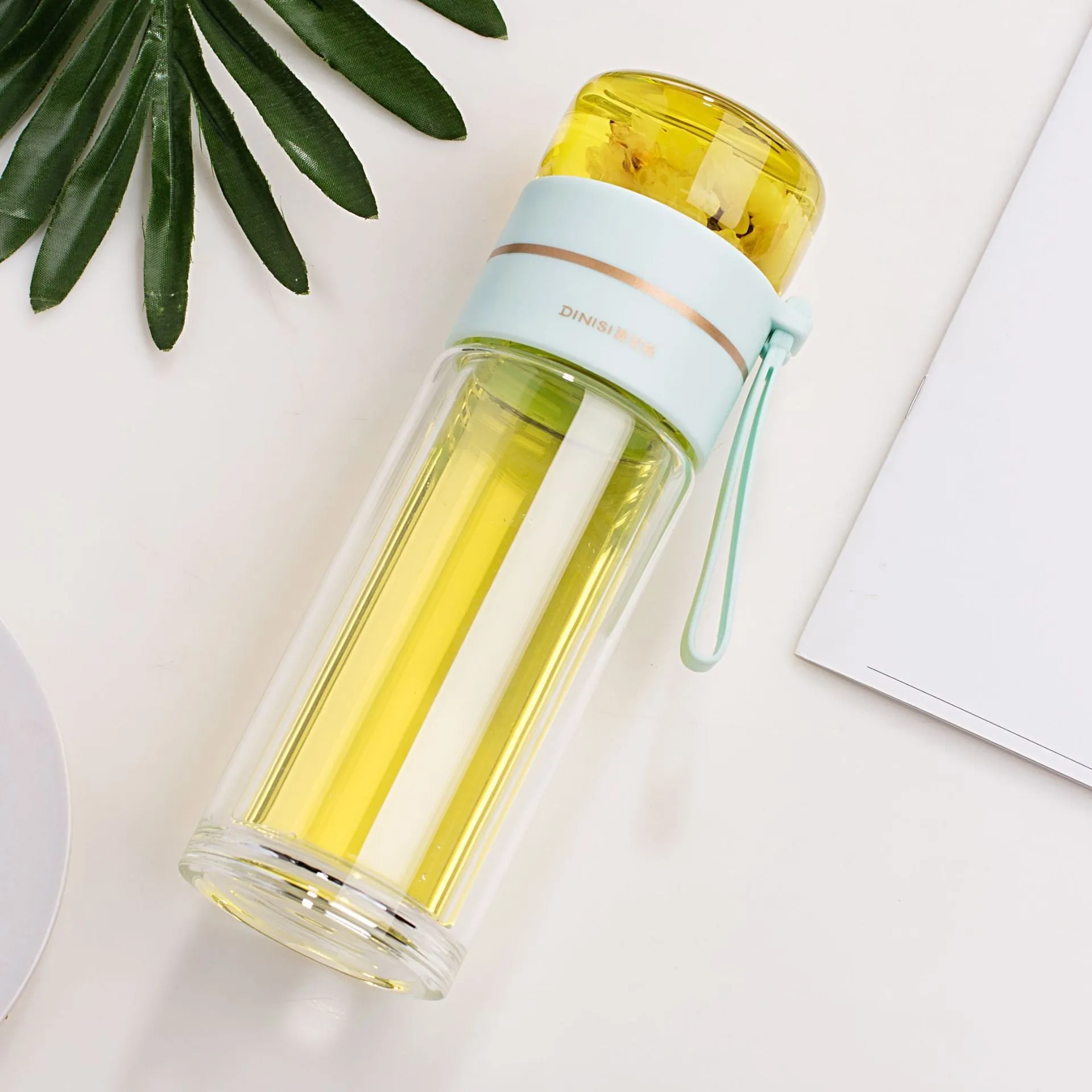 Green double-wall glass water bottle with a stainless steel tea infuser insert and a black leak-proof lid with rope handle.