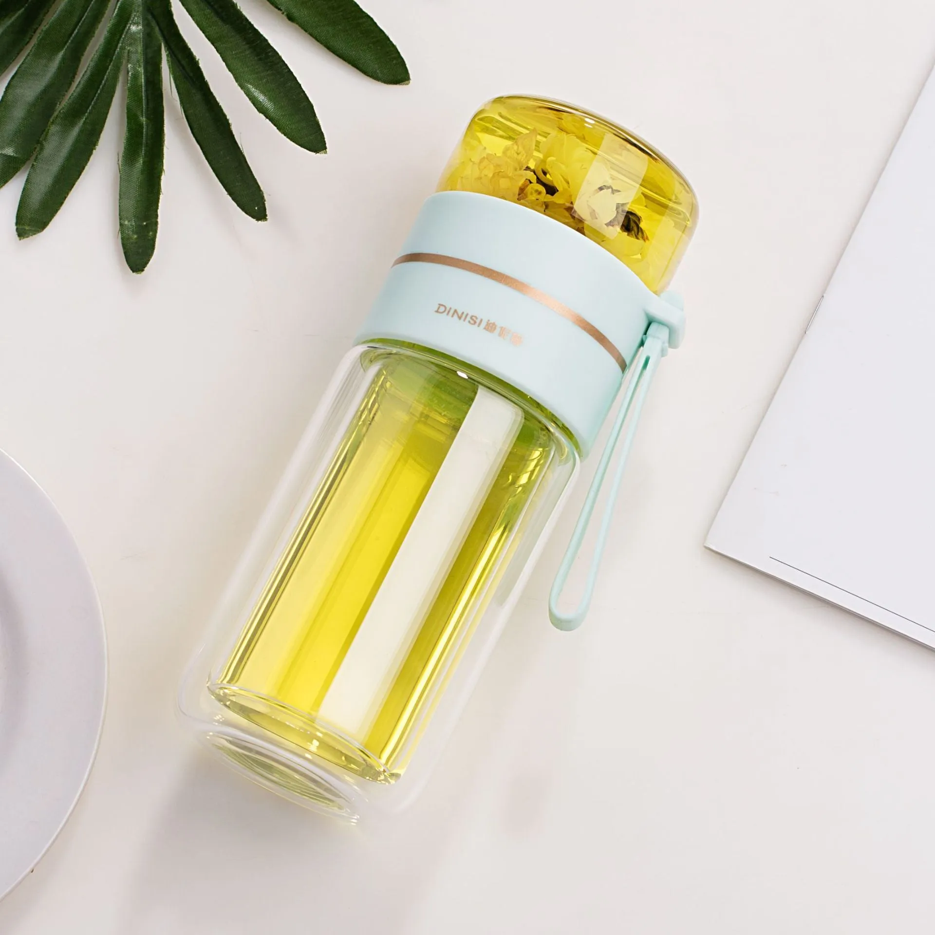 Green double-wall glass water bottle with a stainless steel tea infuser insert and a black leak-proof lid with rope handle.