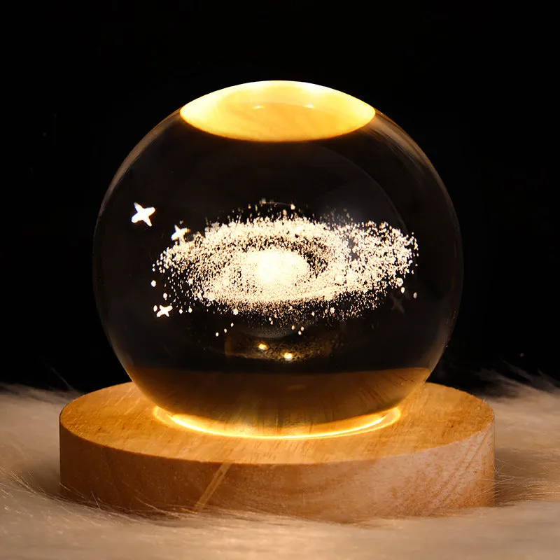 LED galaxy crystal ball night light with 3D planet designs on a table