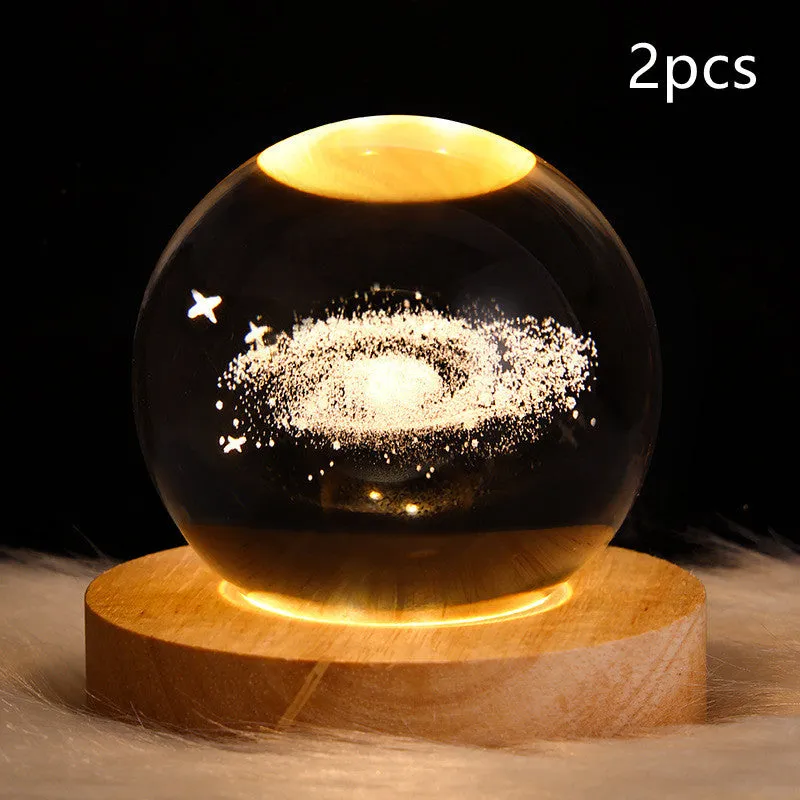 LED galaxy crystal ball night light with 3D planet designs on a table
