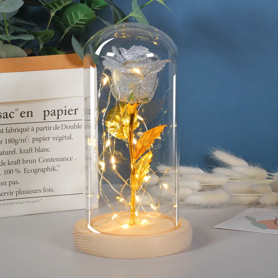 Glass dome covering a red eternal rose with coiled battery-powered LED lights on bendable copper wire.