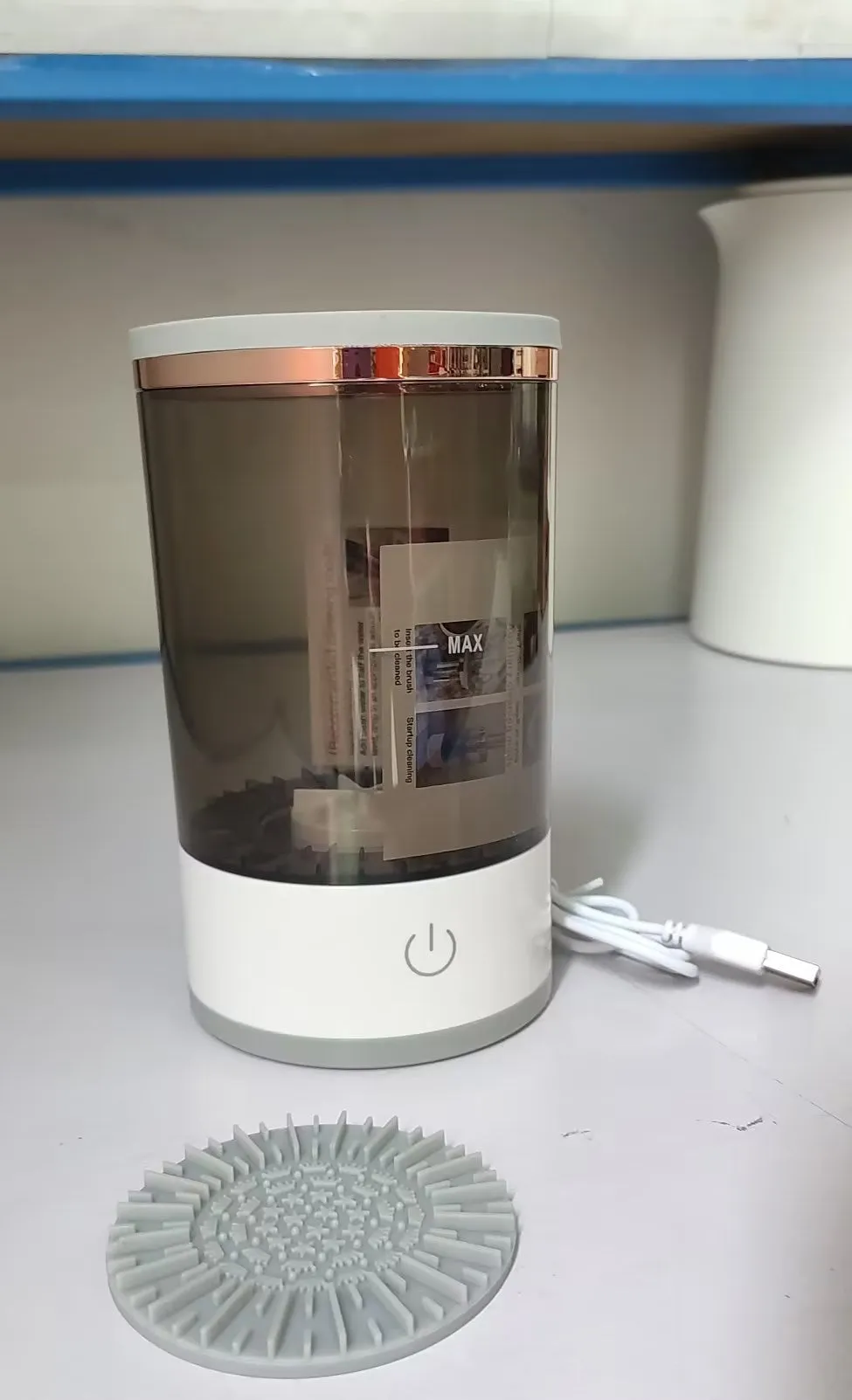 Grey and white portable electric makeup brush cleaner with USB cable.