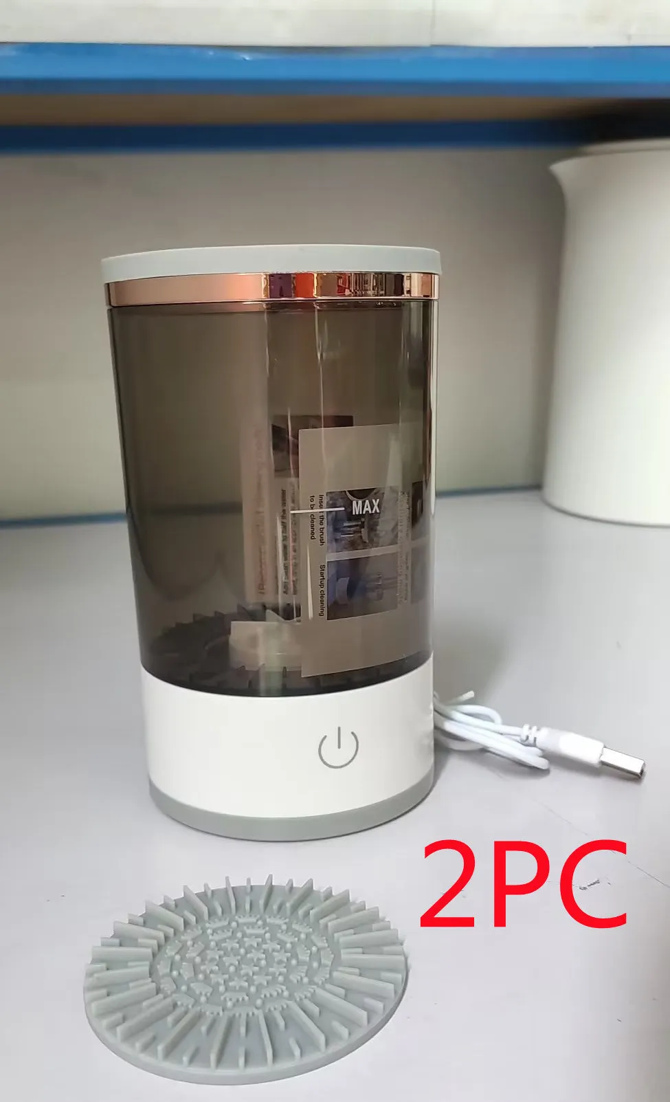 Grey and white portable electric makeup brush cleaner with USB cable.