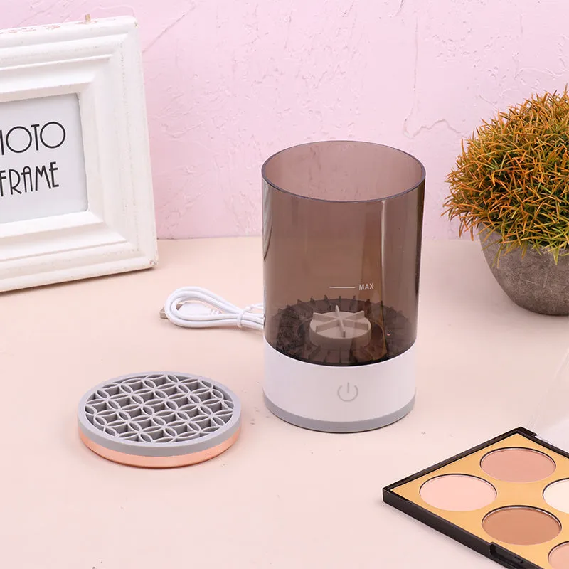 Grey and white portable electric makeup brush cleaner with USB cable.