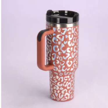 40 oz stainless steel insulated tumbler with a black handle, straw, and grey lid on a wooden table