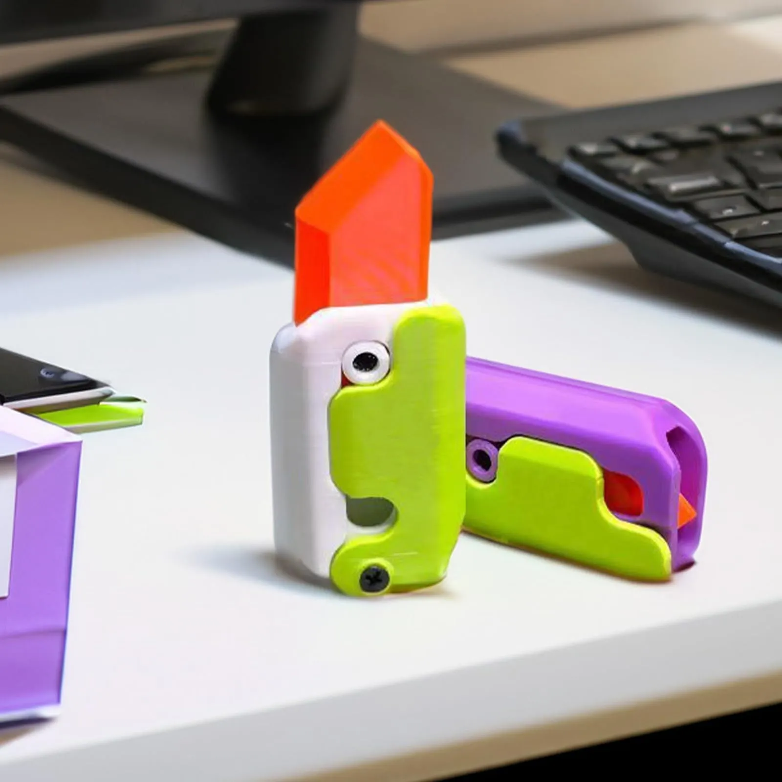 3D printed carrot gravity fidget knife in orange purple green colour, showing blade partly extended from sheath