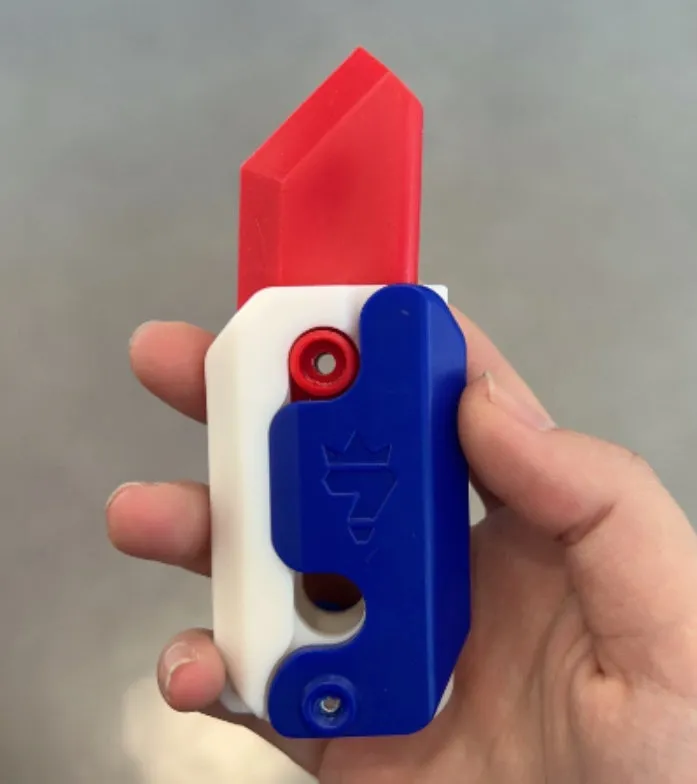 3D printed carrot gravity fidget knife in orange purple green colour, showing blade partly extended from sheath