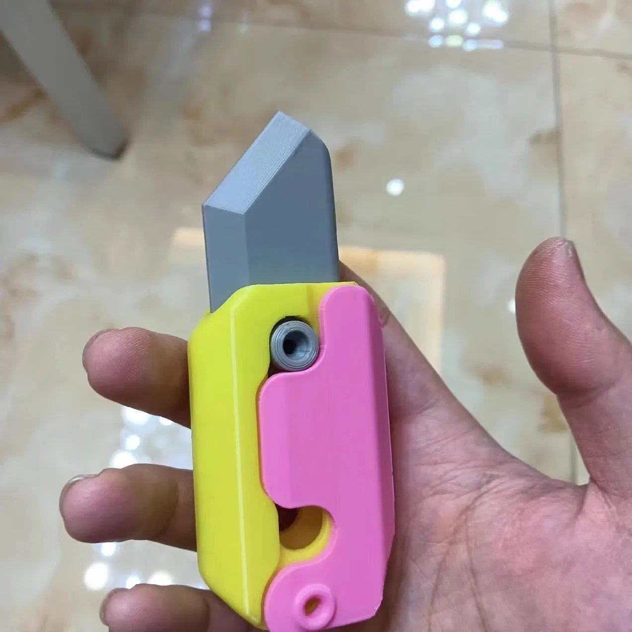 3D printed carrot gravity fidget knife in orange purple green colour, showing blade partly extended from sheath
