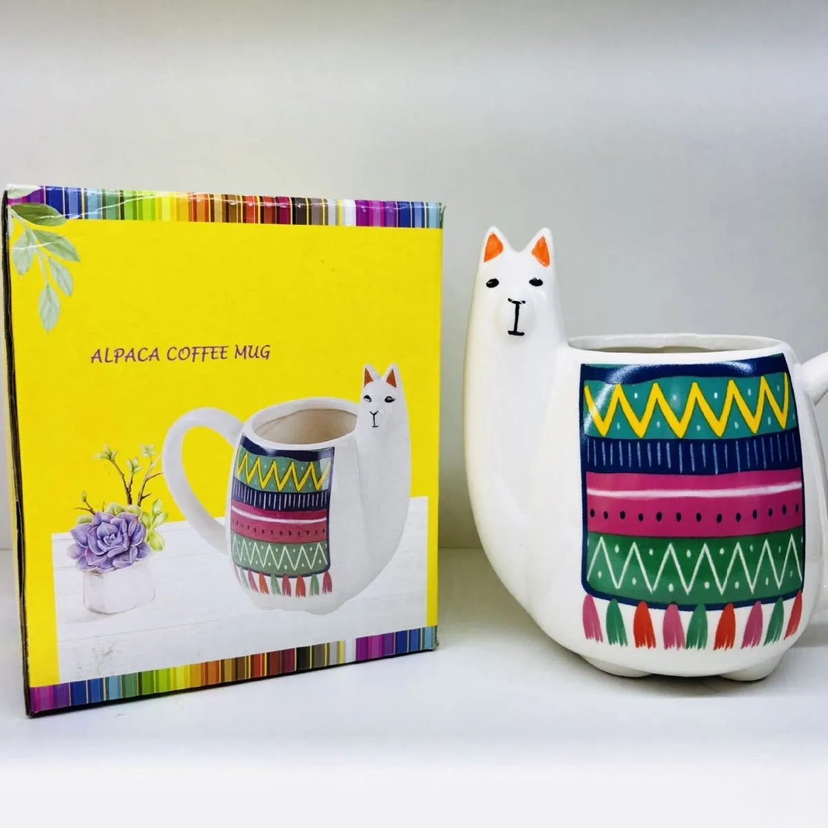 Colourful cartoon alpaca design on a white ceramic mug with a handle.