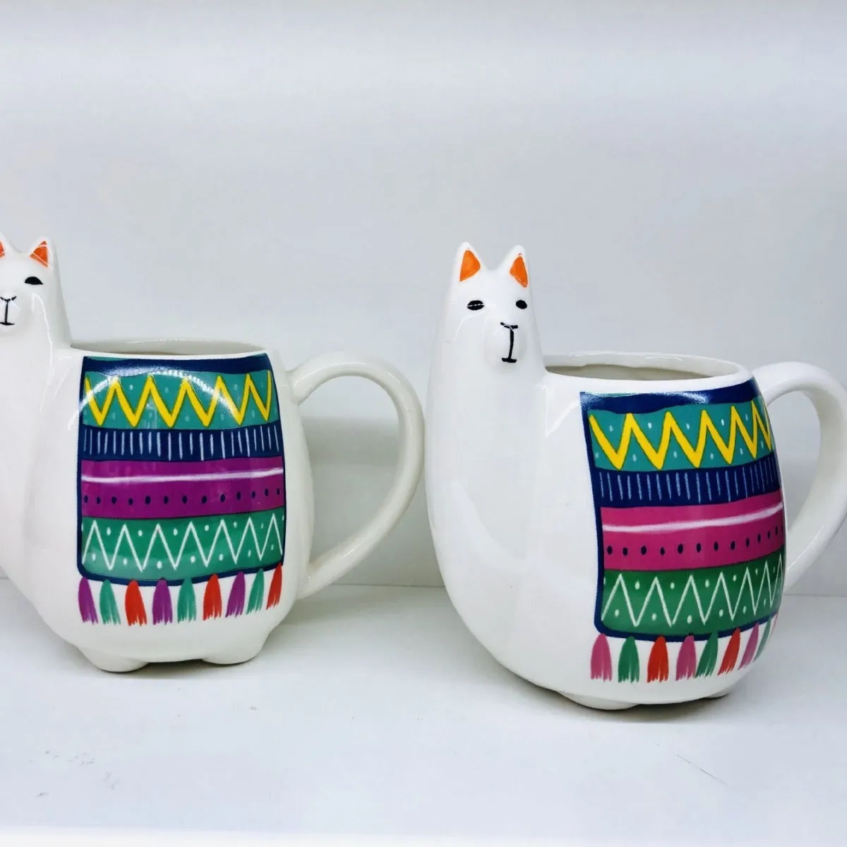 Colourful cartoon alpaca design on a white ceramic mug with a handle.