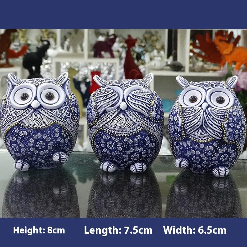 Three blue and white owl resin ornaments in large and small sizes on a white shelf