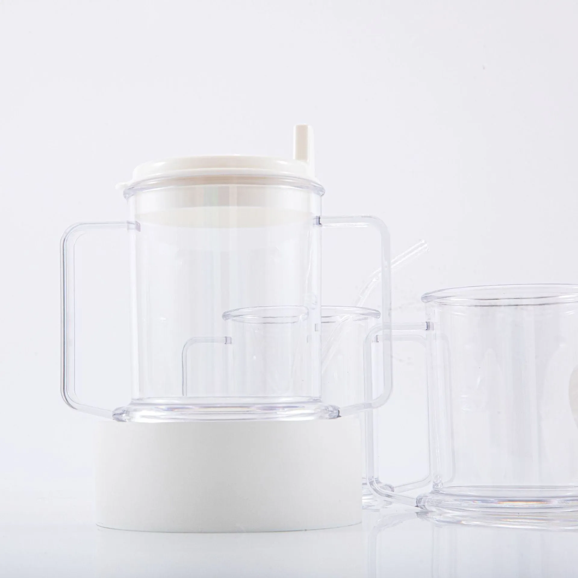 Transparent plastic drinking cup with a grey spill-proof lid on a white background.