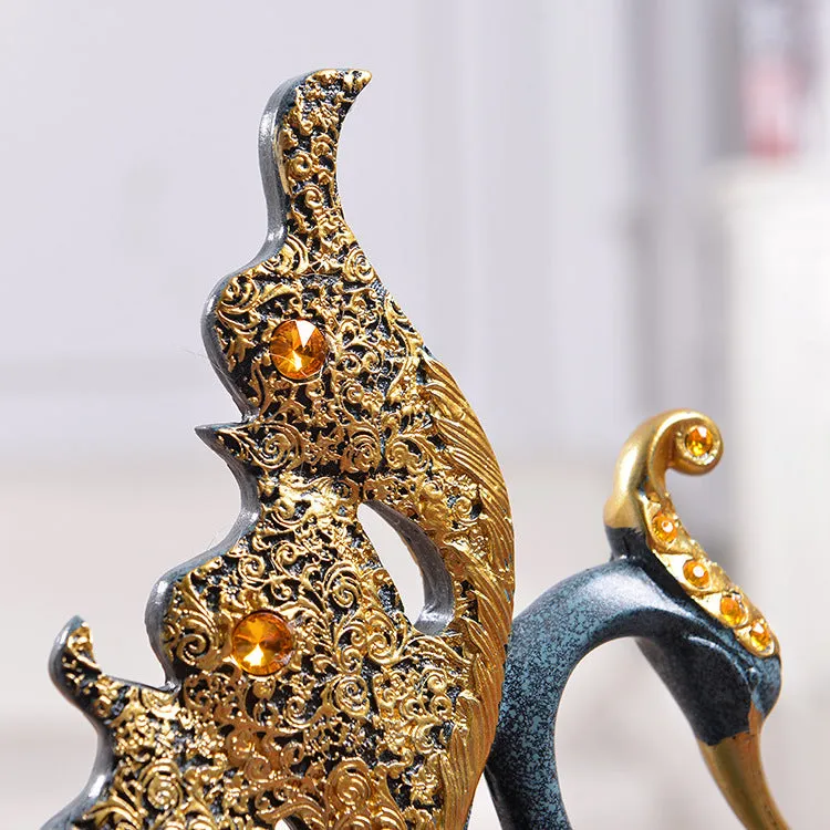 Resin couple swan figurines in blue and gold, large 29cm and small 24cm, on a wooden table
