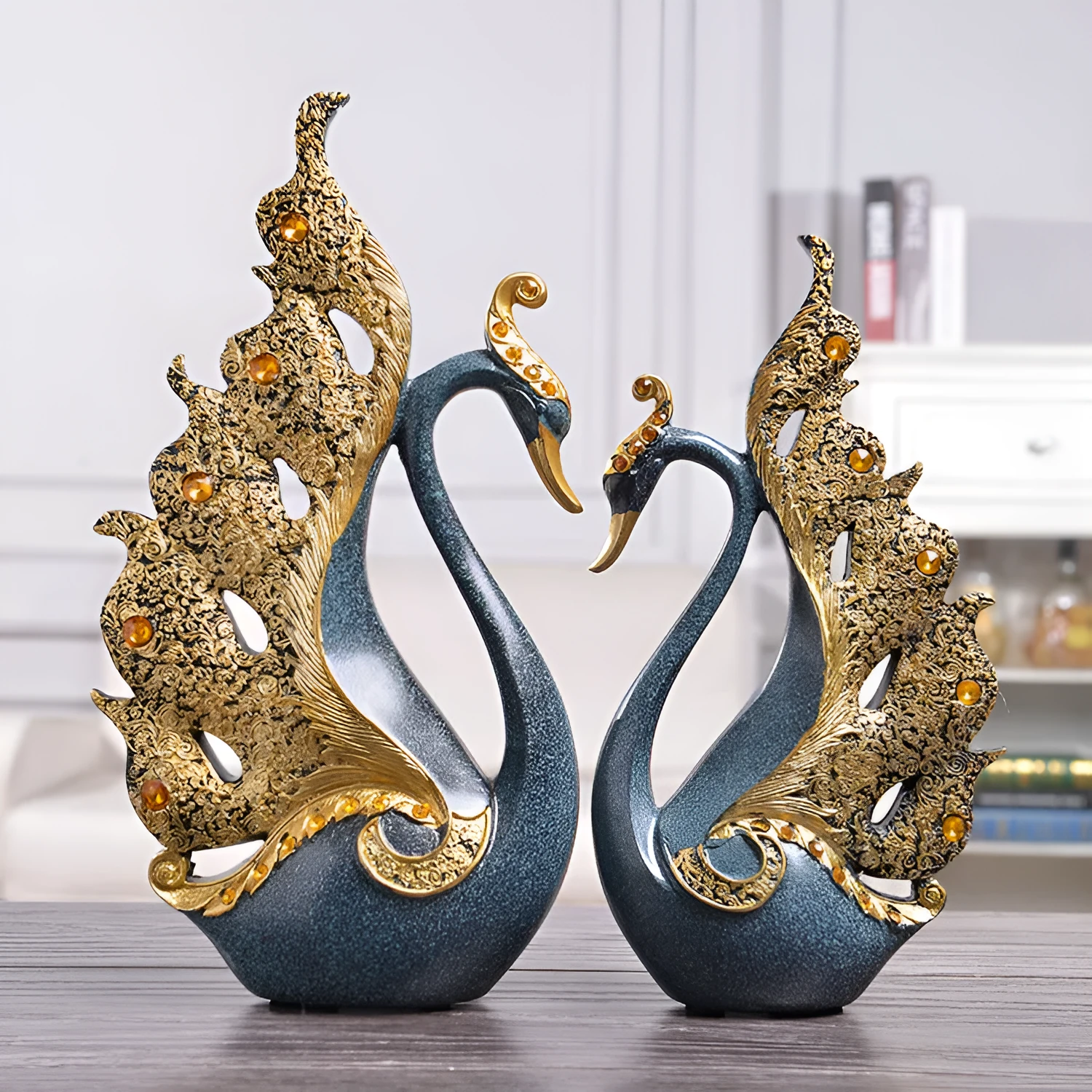 Resin couple swan figurines in blue and gold, large 29cm and small 24cm, on a wooden table