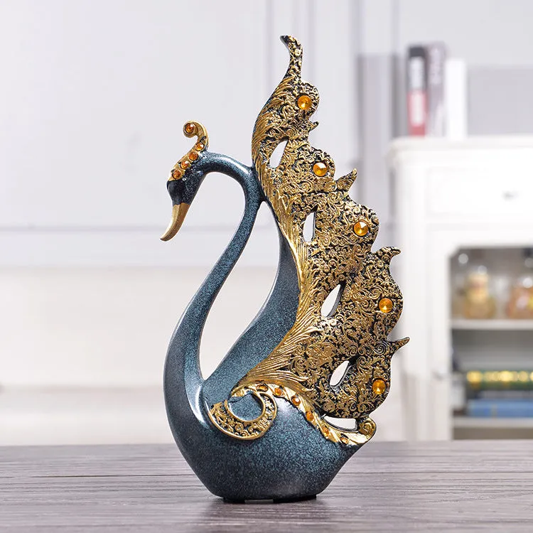 Resin couple swan figurines in blue and gold, large 29cm and small 24cm, on a wooden table